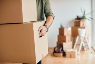 Close-up of man carrying cardboard boxes while relocating into new apartment. Close-up of a man with carton boxes moving into new home.